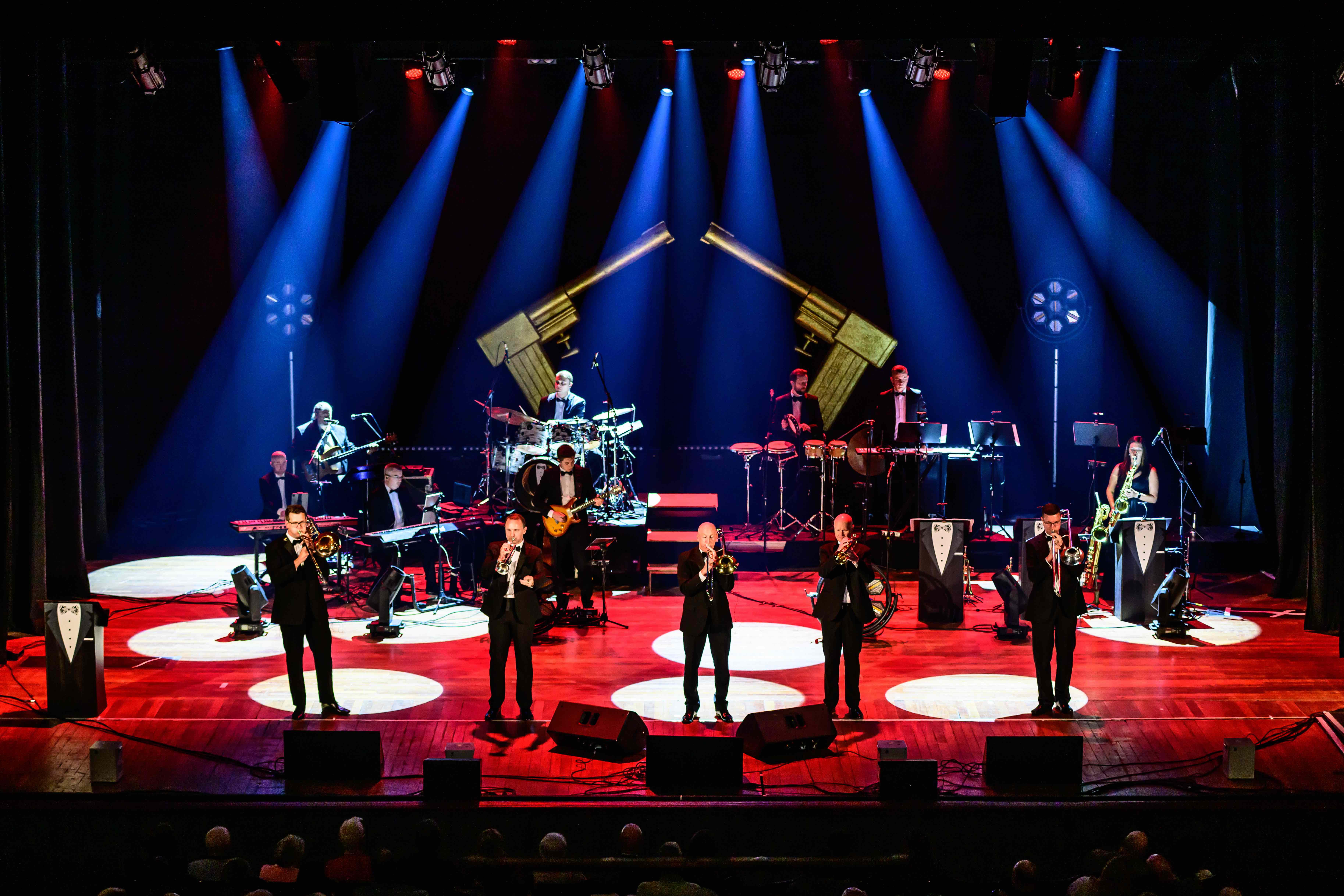 James Bond Themed Concert Spectacular featuring singers and a band on a theatre stage