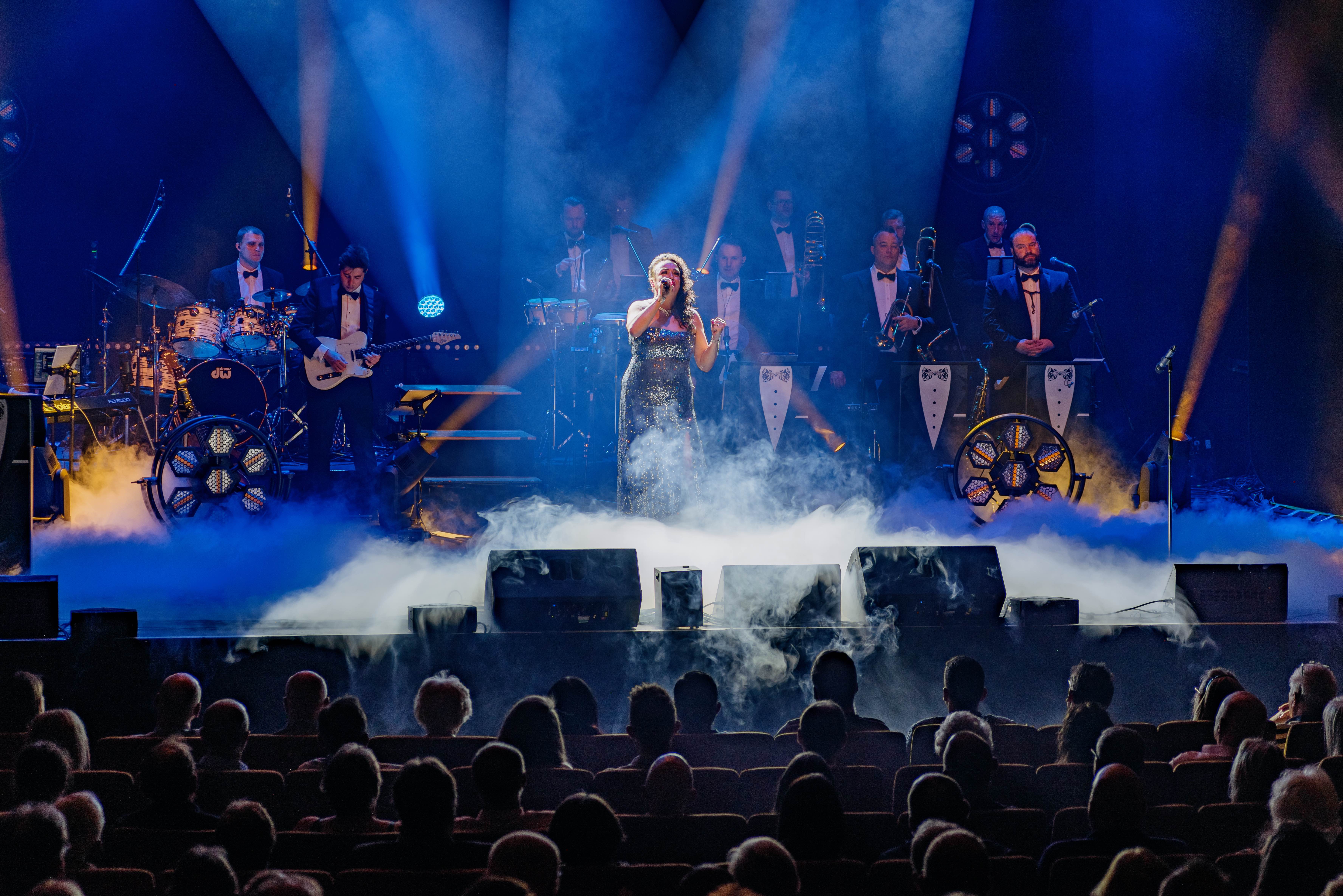 James Bond Themed Concert Spectacular featuring singers and a band on a theatre stage