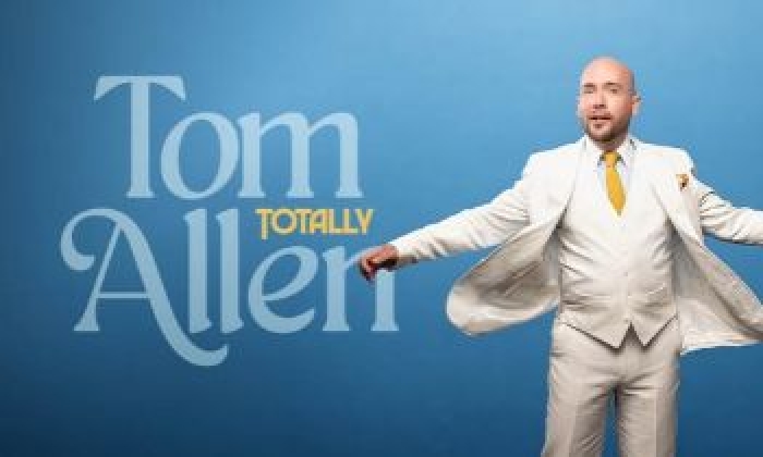 Comedian Tom Allen wearing a white suit to advertise his upcoming appearance at The Victoria Theatre Halifax